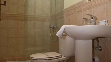 A bathroom with a glass-enclosed shower, a toilet, and a sink.