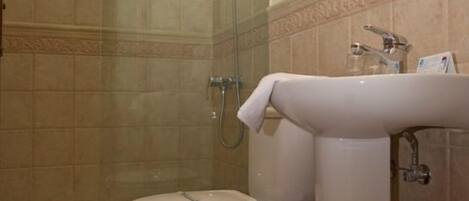 A bathroom with a glass-enclosed shower, a toilet, and a sink.