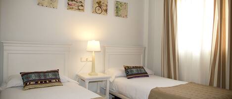 A hotel room with two beds, a nightstand with a lamp, and wall art depicting bicycles.