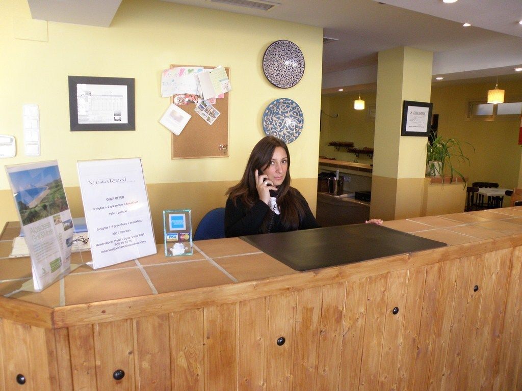 A reception desk with a wooden counter, a bulletin board with papers, and a framed certificate on the wall.