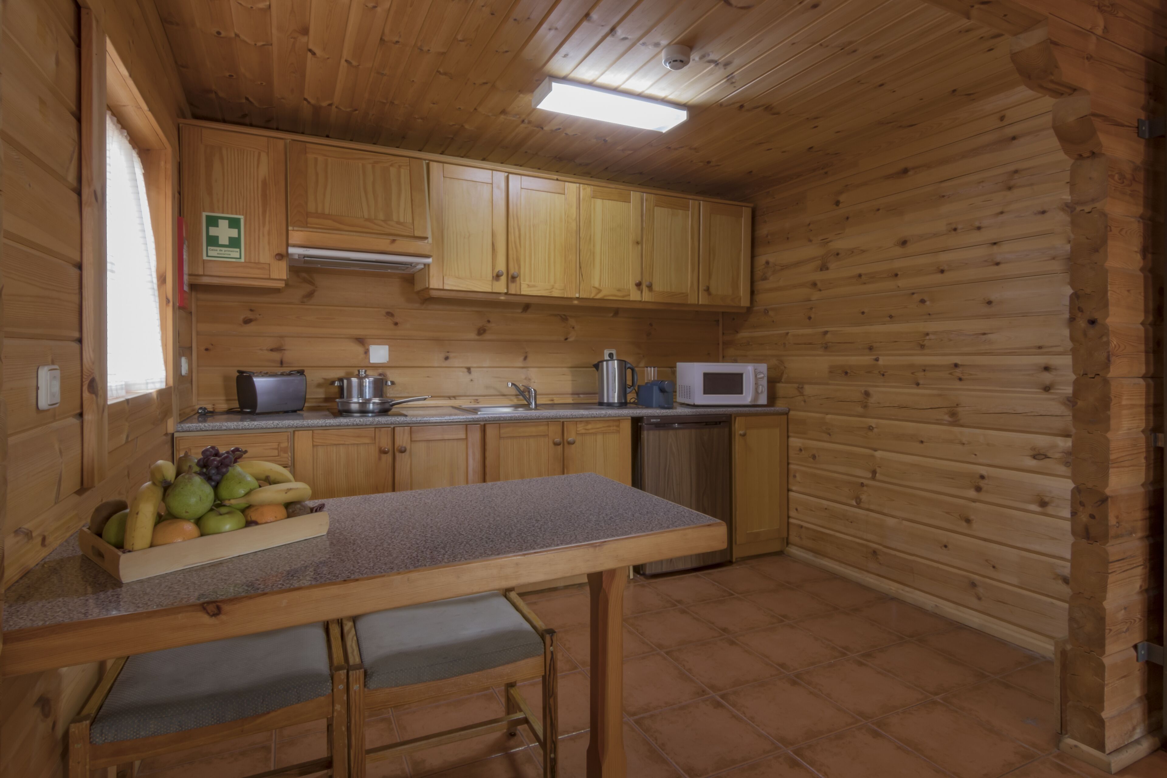 Eine Holzhütte mit einer Küche, inklusive Arbeitsplatte, Spüle, Schränken und einer Mikrowelle.