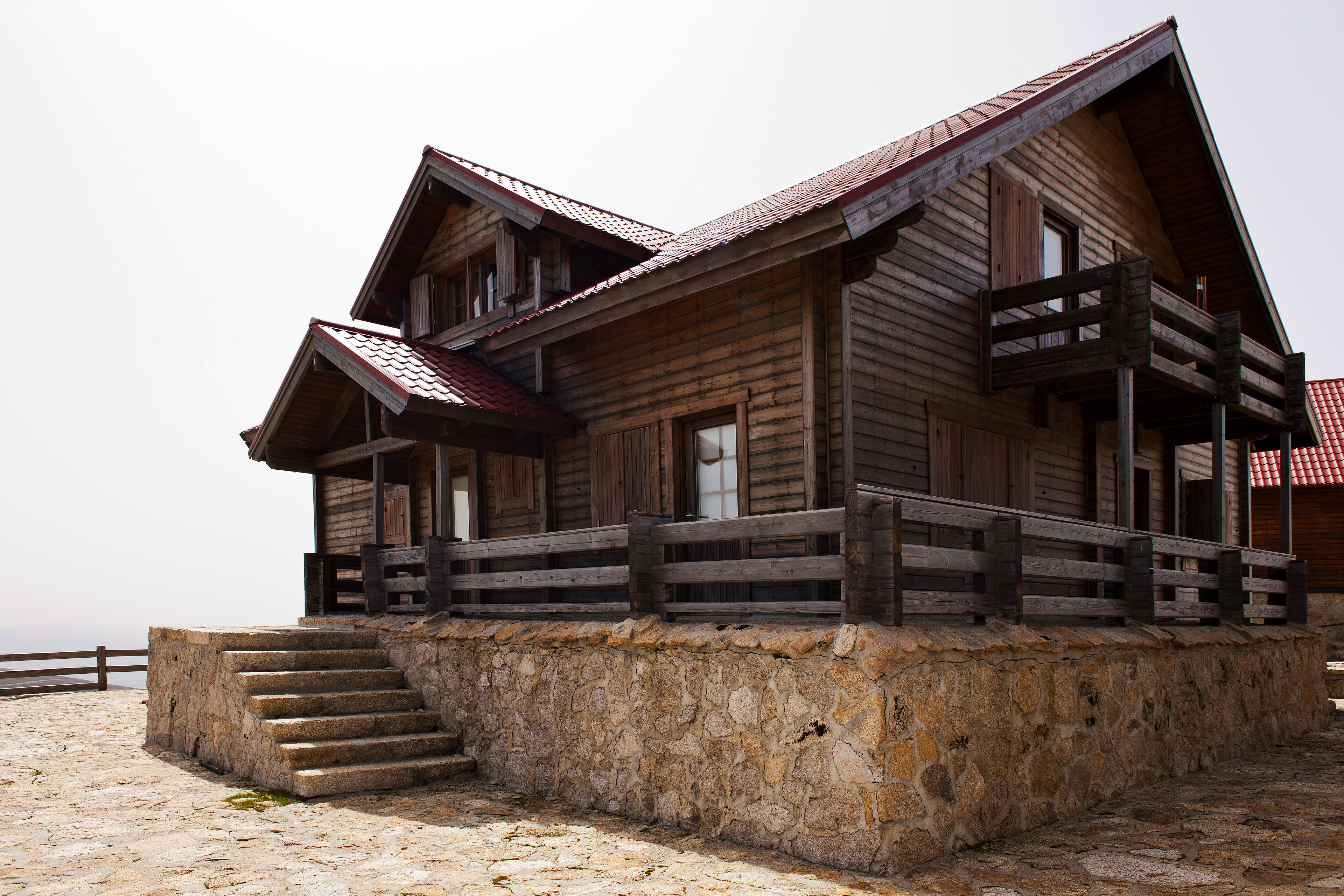 A wooden building with a stone base, a balcony, and a staircase leading up to the entrance.