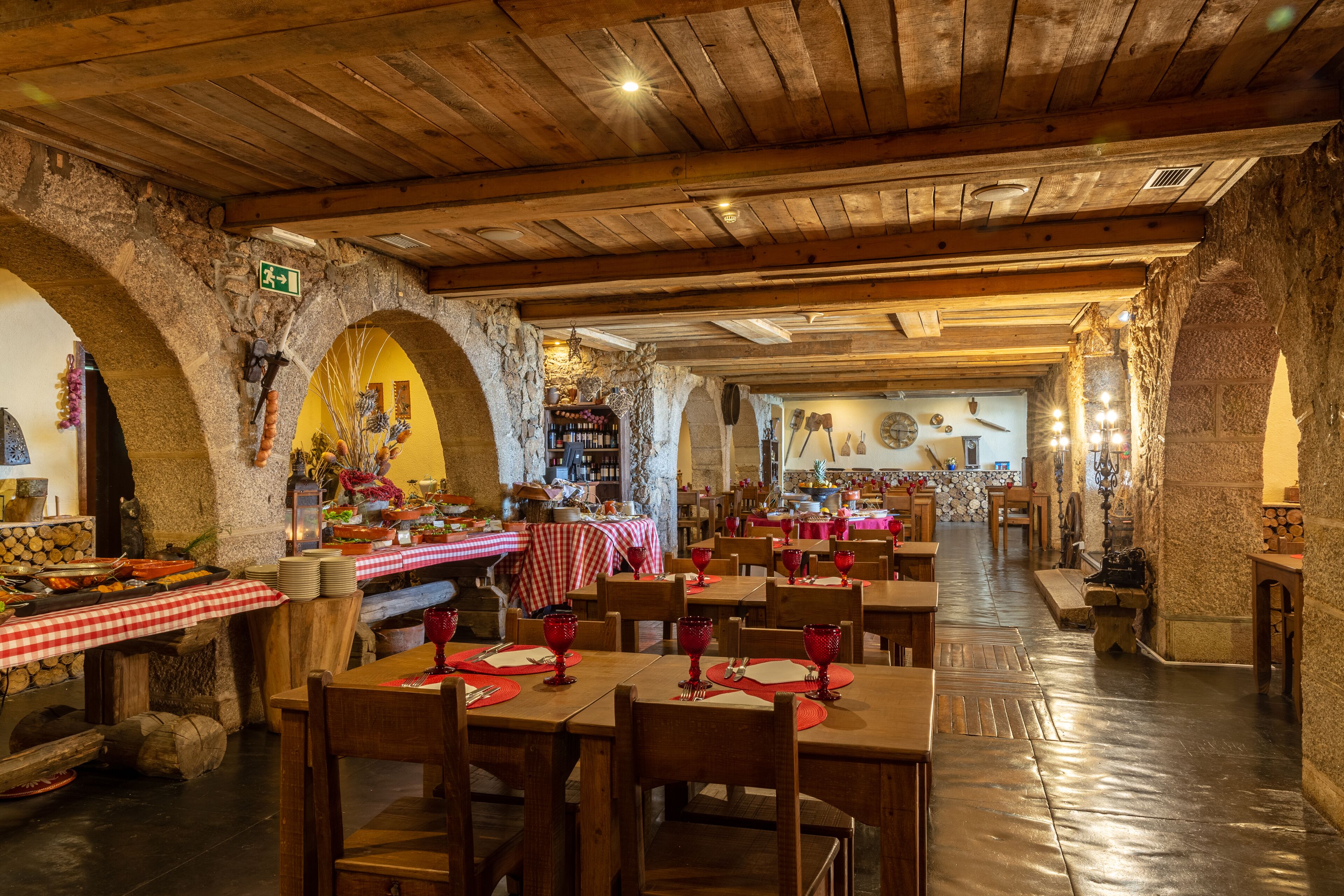 Un restaurant doté d’arches en pierre, de tables en bois et de nappes à carreaux rouges et blancs.