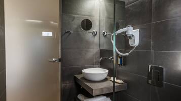 A modern bathroom with a glass shower enclosure, a white toilet, and a vanity with a sink and mirror.