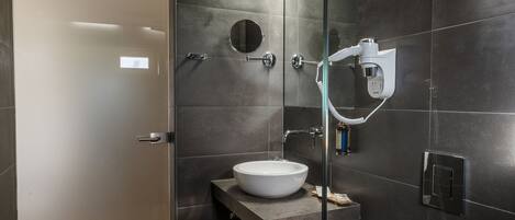 A modern bathroom with a glass shower enclosure, a white toilet, and a vanity with a sink and mirror.