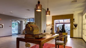 A spacious lobby with a wooden table, red rug, and hanging pendant lights. - Puralã - Wool Valley Hotel & SPA (Covilhã)