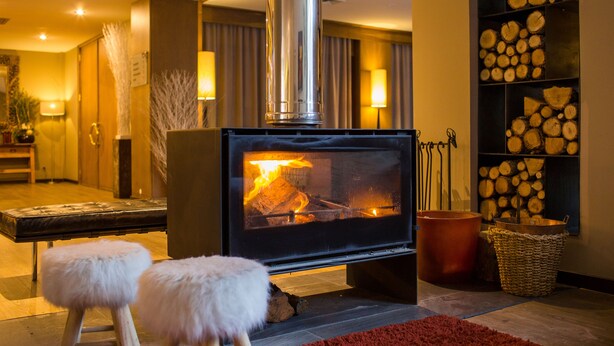 A modern living room with a wood-burning stove, a bench, and a fireplace. - Puralã - Wool Valley Hotel & SPA (Covilhã)