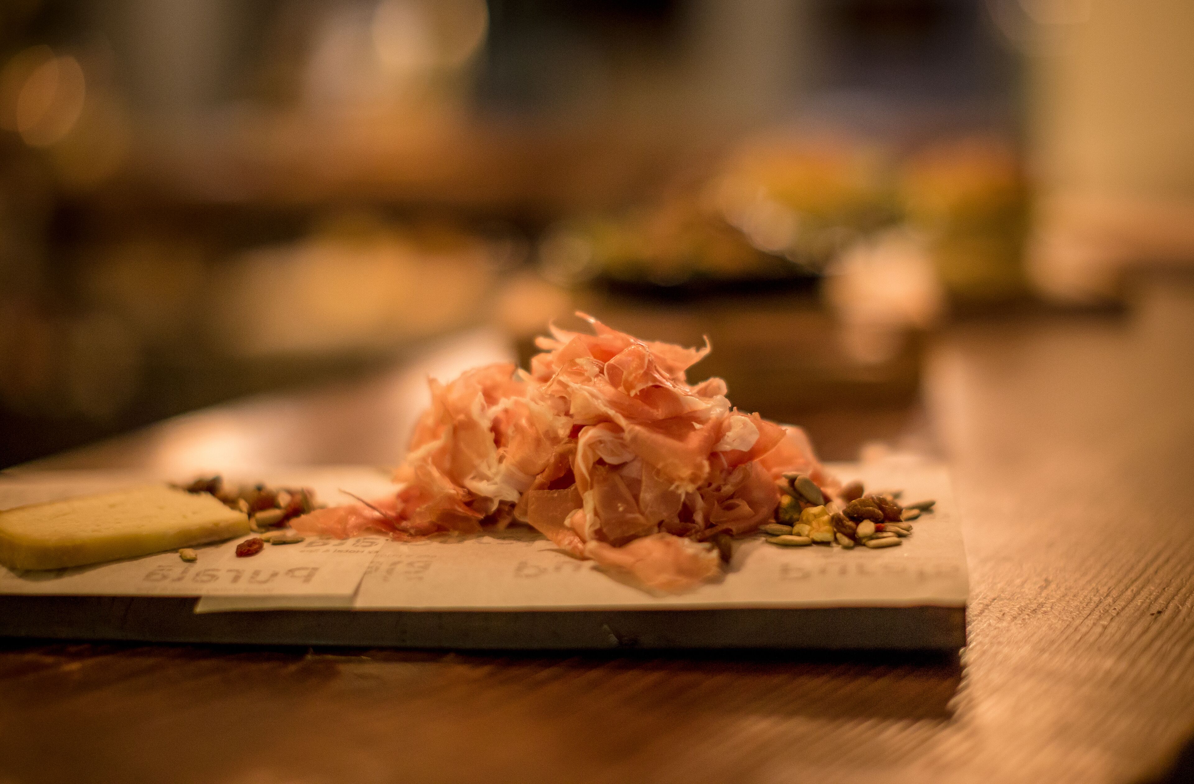 A plate with shredded meat and nuts on a wooden table.