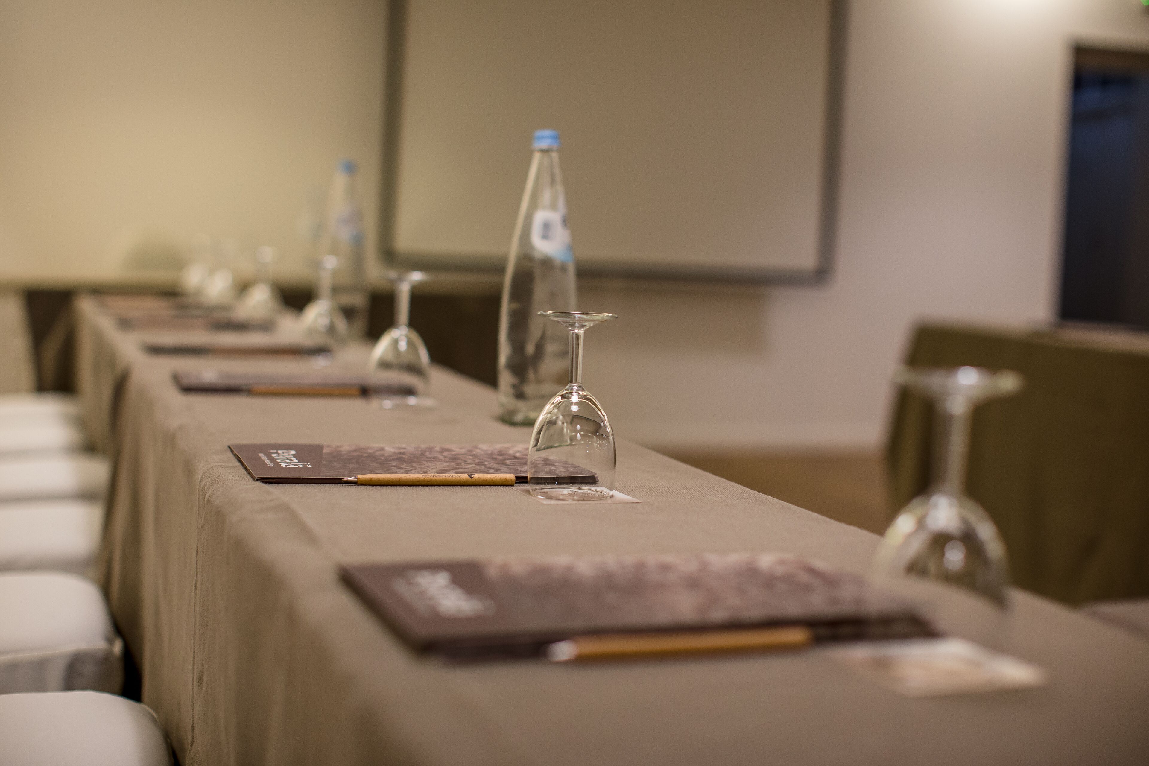 A conference room with a long table set for a meeting, equipped with water bottles, wine glasses, and nameplates.