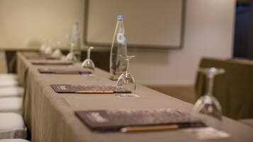 A conference room with a long table set for a meeting, equipped with water bottles, wine glasses, and nameplates.