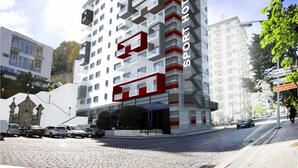A modern hotel with a unique geometric facade, multiple balconies, and a prominent red logo. - Sport Hotel Gym + SPA (Covilhã)