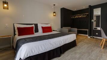A modern bedroom with a large bed, bedside tables, a desk, a chair, and a mirror.