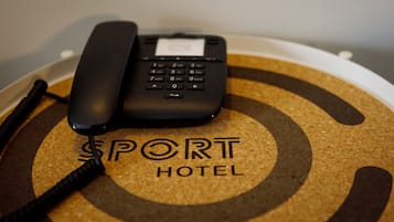 A black telephone on a corkboard with the text "SPORT HOTEL" visible.