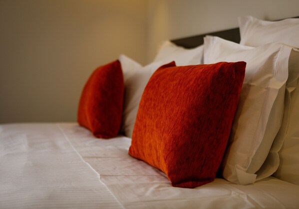 A bed with white linens and red and beige pillows. - Sport Hotel Gym + SPA (Covilhã)
