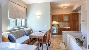 A compact living space with a dining area, kitchen, and a small seating area by the window.