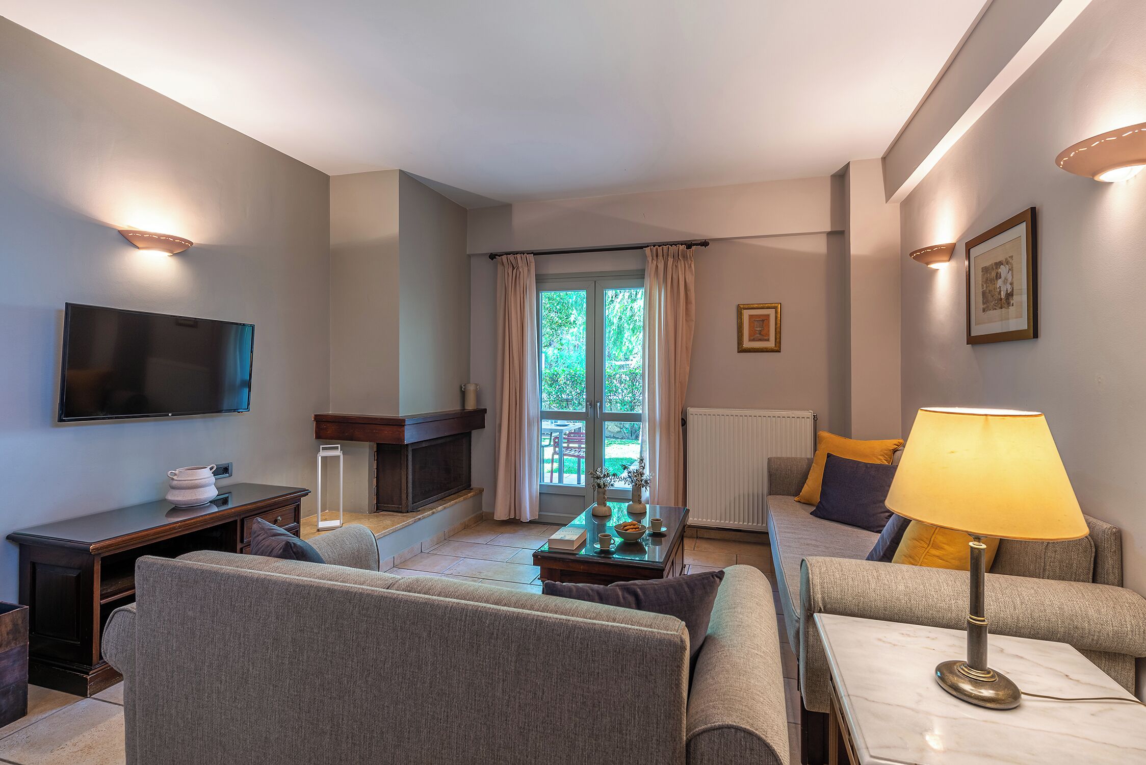A modern living room with a flat-screen TV, sofa, coffee table, and lamp.