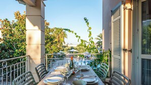 An outdoor dining area with a table set for four, surrounded by chairs, and a view of the garden and trees in the background.