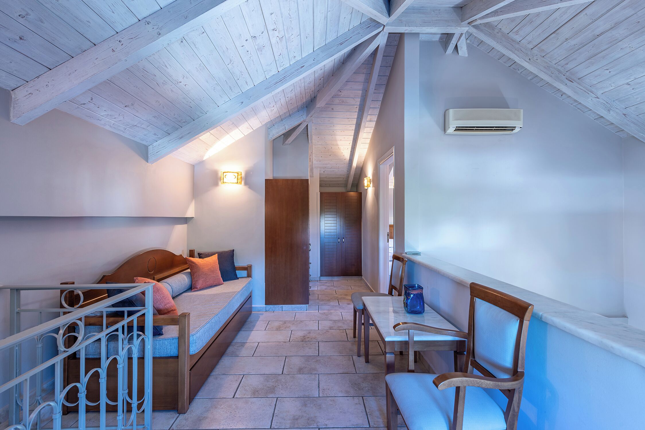 Une pièce avec un plafond en pente, un lit, une table avec des chaises et un appareil de climatisation.