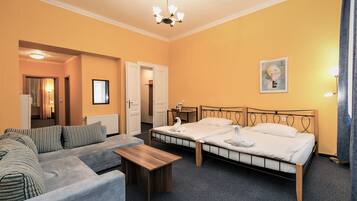 A hotel room with a double bed, a sofa, a small table, and a chandelier.