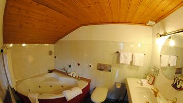 A bathroom with a wooden ceiling, a bathtub, a toilet, and a sink.