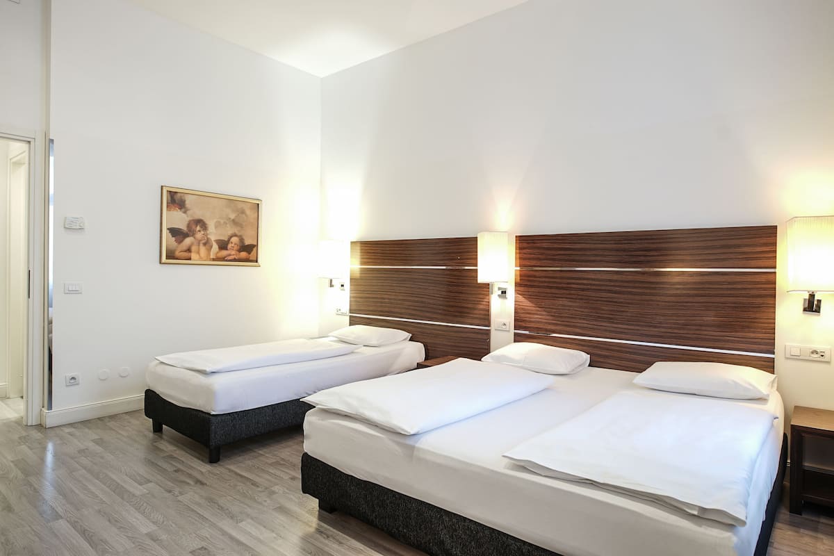 A hotel room with two beds, wooden headboards, white bedding, and a painting on the wall.