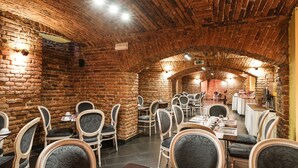 Un restaurante con paredes de ladrillo y techos abovedados, con mesas y sillas dispuestas para comer.