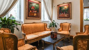 Una habitación con sofá, sillones, una mesa y dos cuadros enmarcados en la pared.
