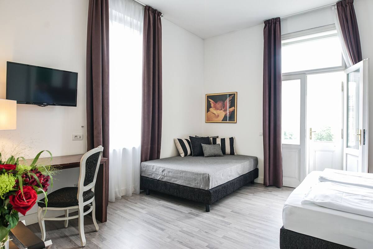 A modern hotel room with a bed, a desk, and a TV.