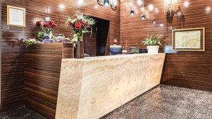 Un mostrador de recepción con encimera de mármol, paneles de madera en las paredes y una araña.