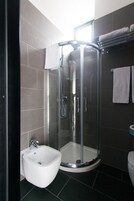Un bagno moderno con doccia vetrata, lavabo a piedistallo bianco e water.