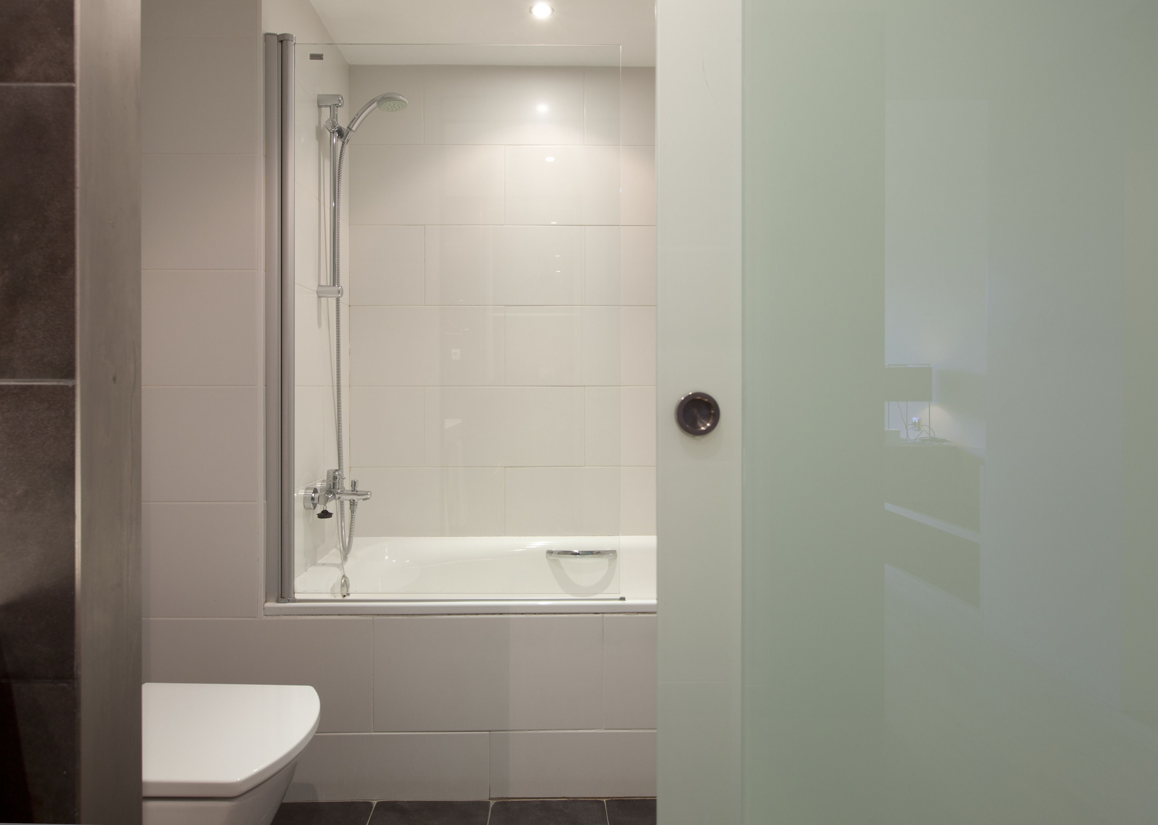 A modern bathroom with a bathtub, toilet, and shower.