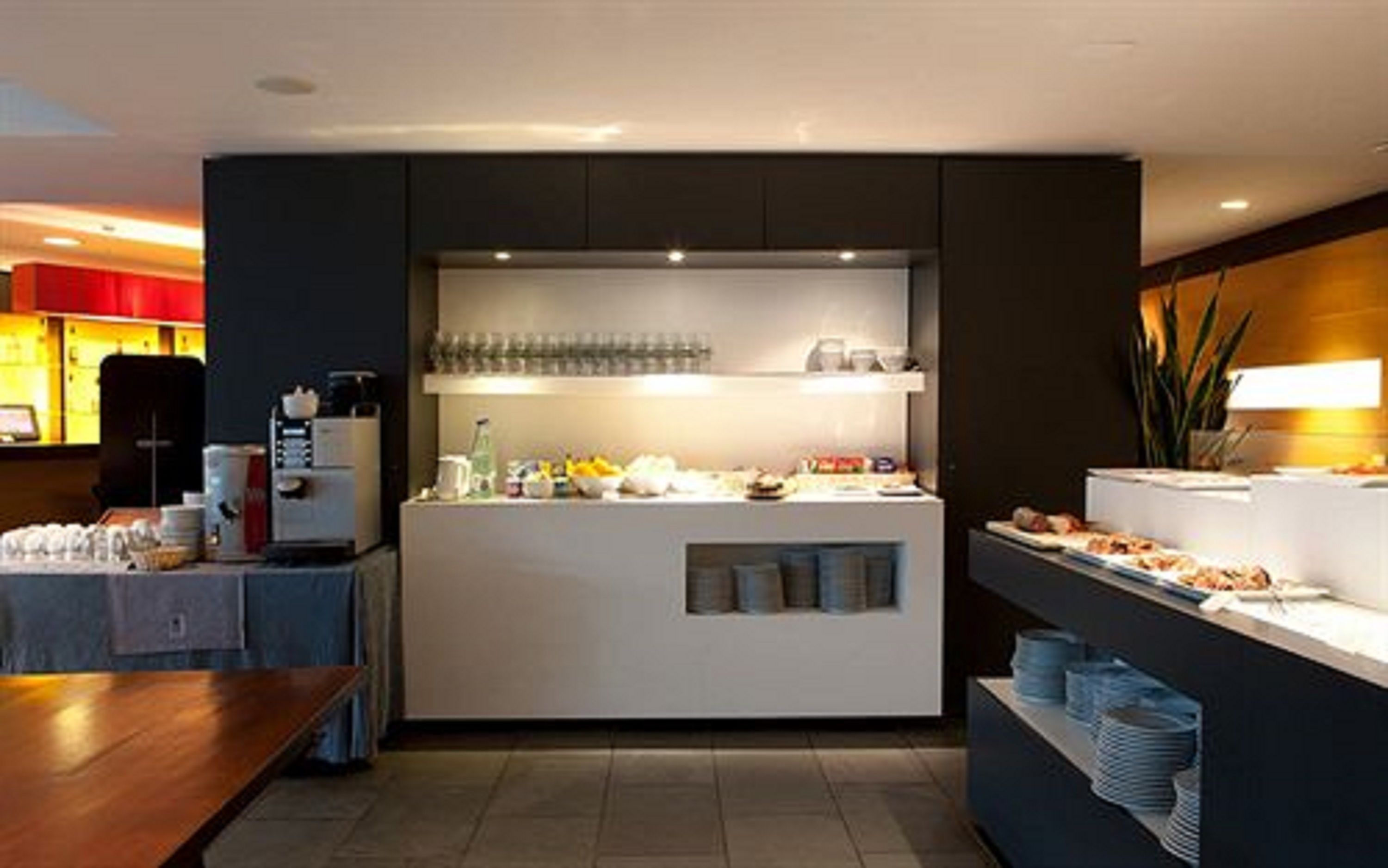 Una cocina moderna con una isla central, equipada con diversos electrodomésticos y un expositor de vidrio.