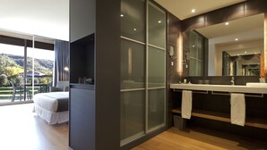 Un baño moderno con un espejo grande, zona de ducha y tocador con toallas.