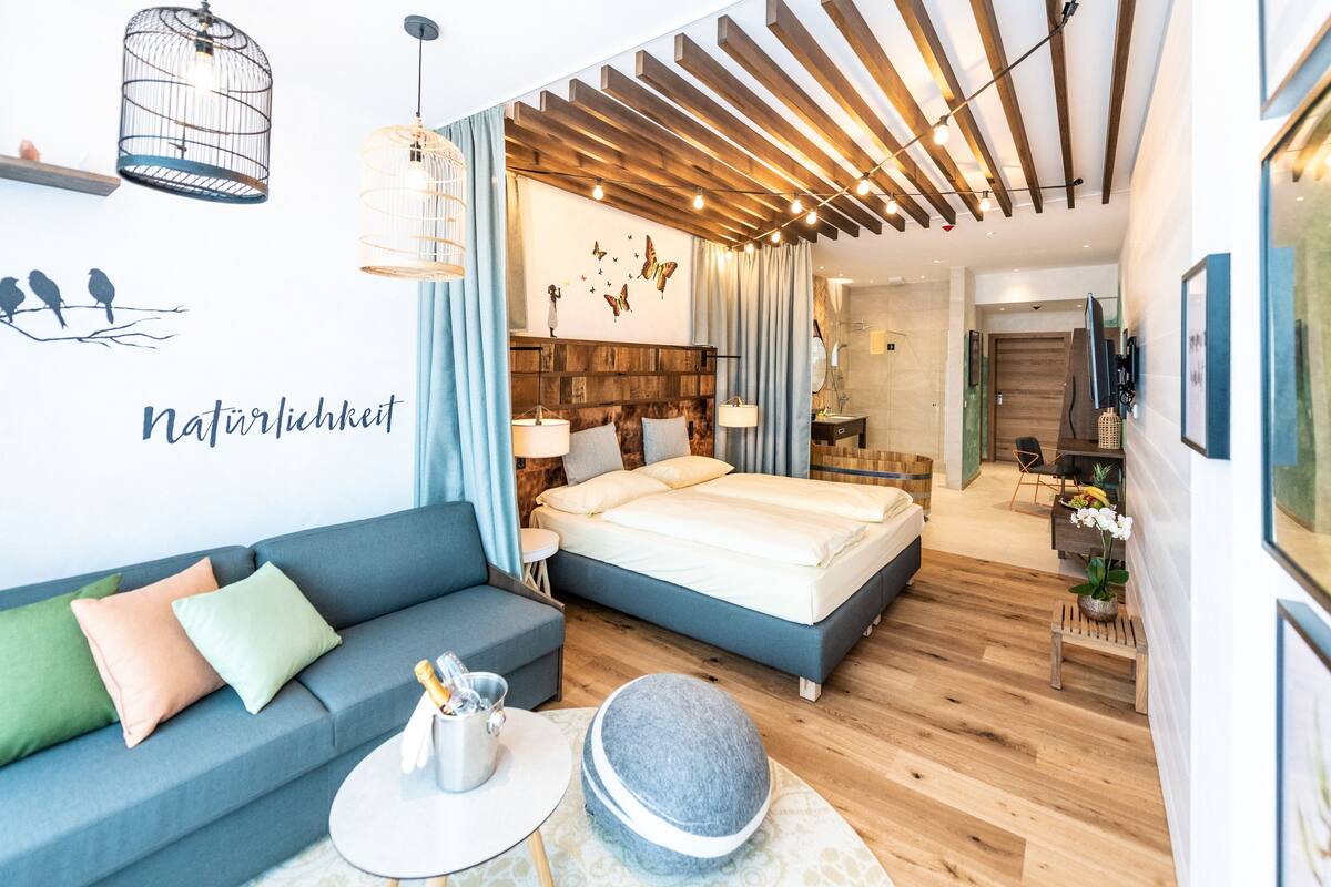 Une chambre moderne avec un lit, un canapé, une petite table et un mur décoratif.