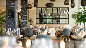 Interior de un restaurante con mesas dispuestas para comer, velas y un menú en una pizarra.