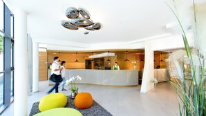Un área de recepción moderna con una recepcionista, un mostrador y un ventanal grande.