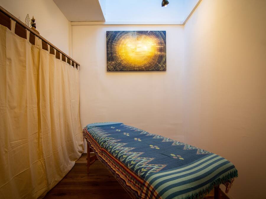 Una habitación estrecha con una cama, una cortina y un cuadro en la pared.