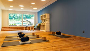 A yoga studio with wooden floors, yoga mats, blocks, and a view of a mountain through large windows. - Hotel Bristol (Saas-Fee)