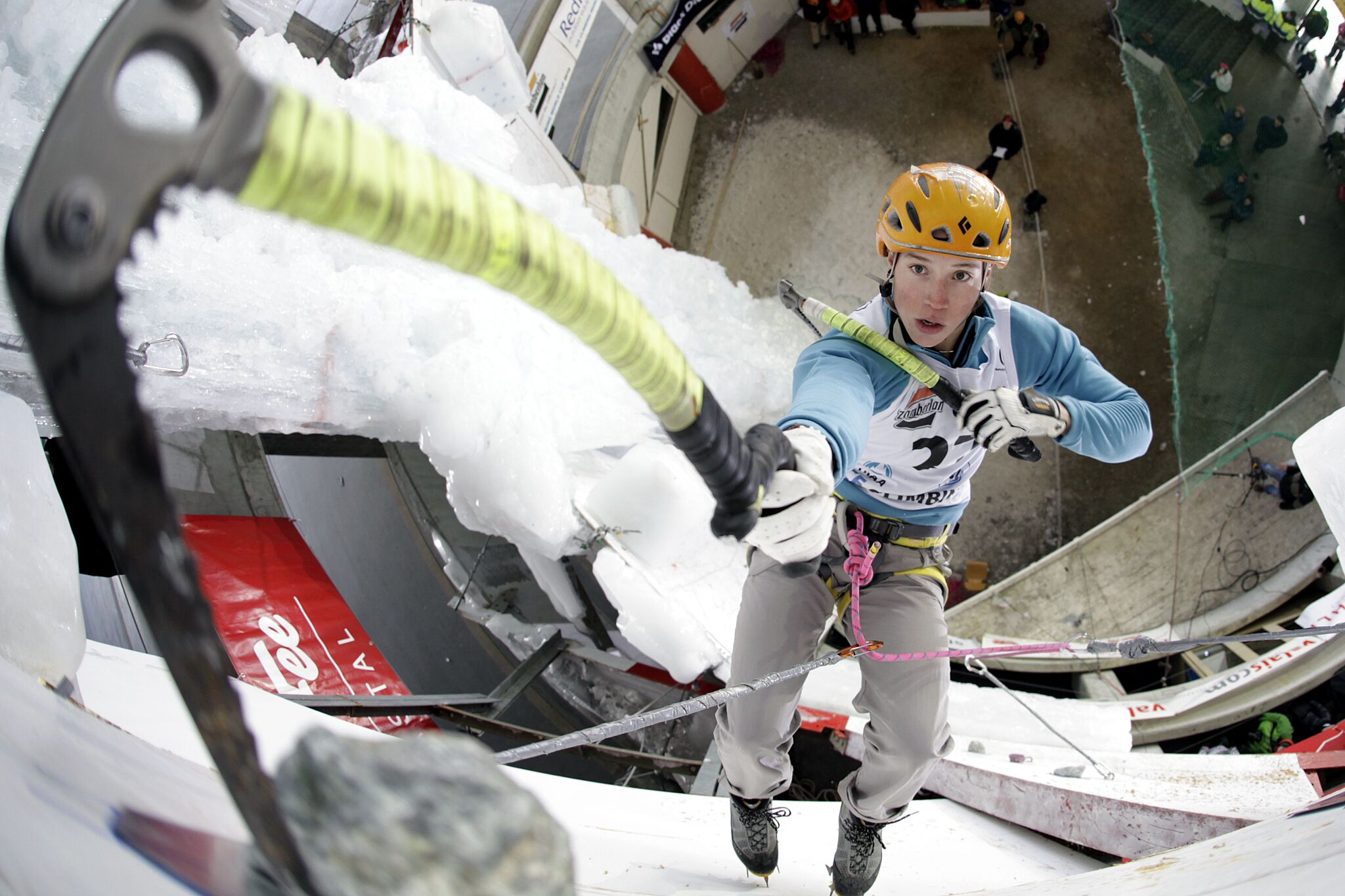 Eine Person mit Klettergurt und Helm, die sich auf eine Winteraktivität vorbereitet.
