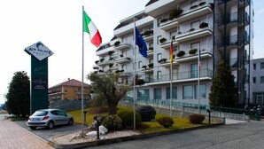 Un hotel de varios pisos con balcones, un letrero que dice 'Air Palace Hotel' y banderas, incluyendo la bandera italiana.