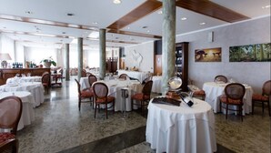 Un amplio comedor con mesas redondas, sillas y una columna central.