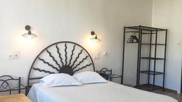 Un dormitorio con una cama, dos lámparas de pared, un estante metálico y una puerta.