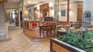 Un vestíbulo de hotel con mostrador de recepción, zona de estar y máquina de café.