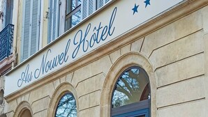 El exterior del Hotel Au Nouver, con una fachada clásica, ventanas arqueadas y un letrero de hotel destacado.