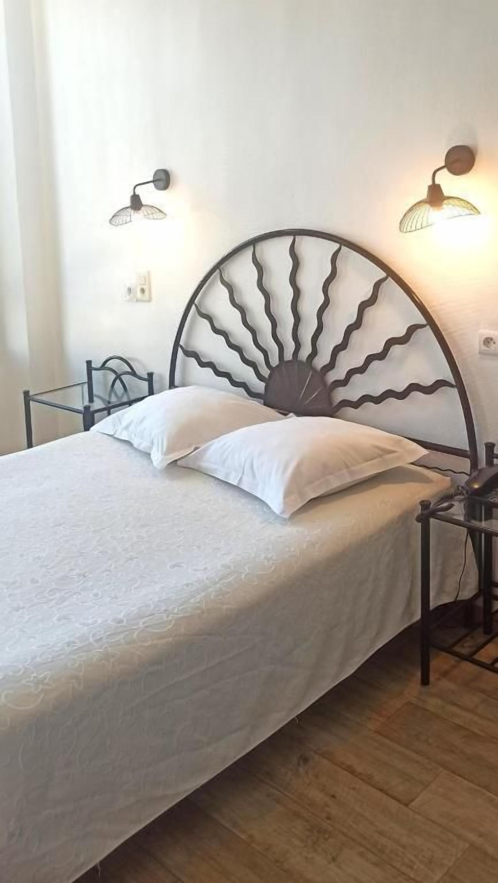Un lit doté d’une tête de lit originale, de deux lampes de chevet et d’un plancher en bois.