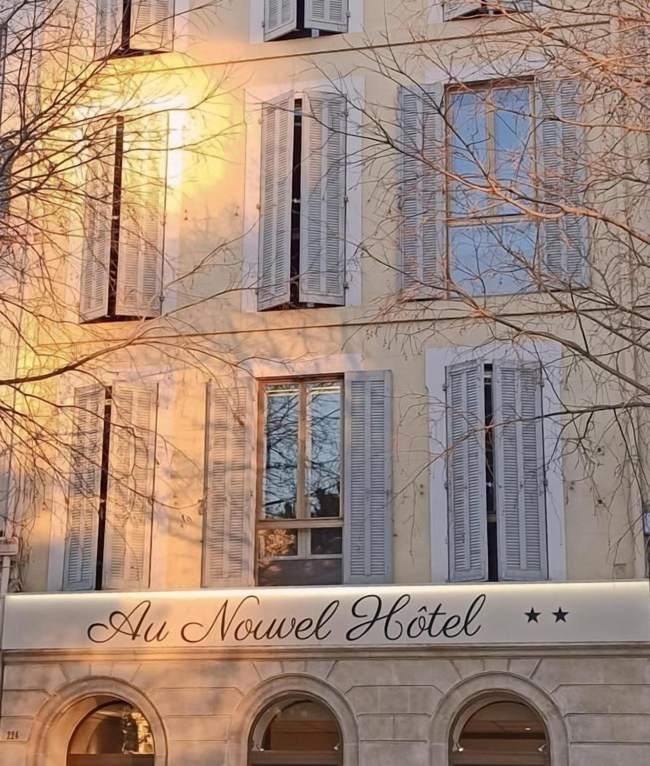 La façade d’un hôtel, ornée de fenêtres en arc de cercle et de volets, avec l’inscription « Au Nouveau Hotel ».