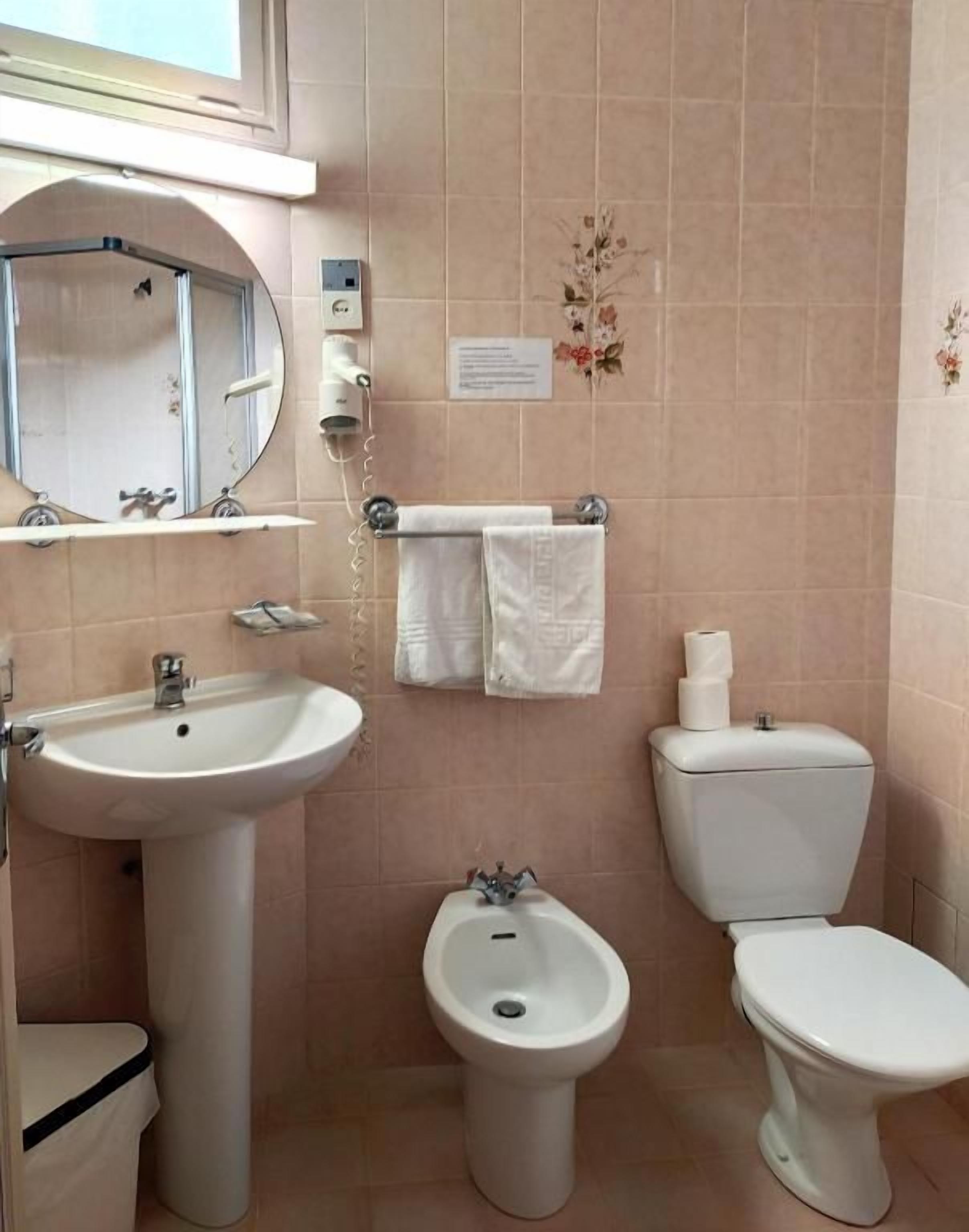 Une salle de bain équipée d’un lavabo, d’un bidet, de toilettes et d’un miroir.