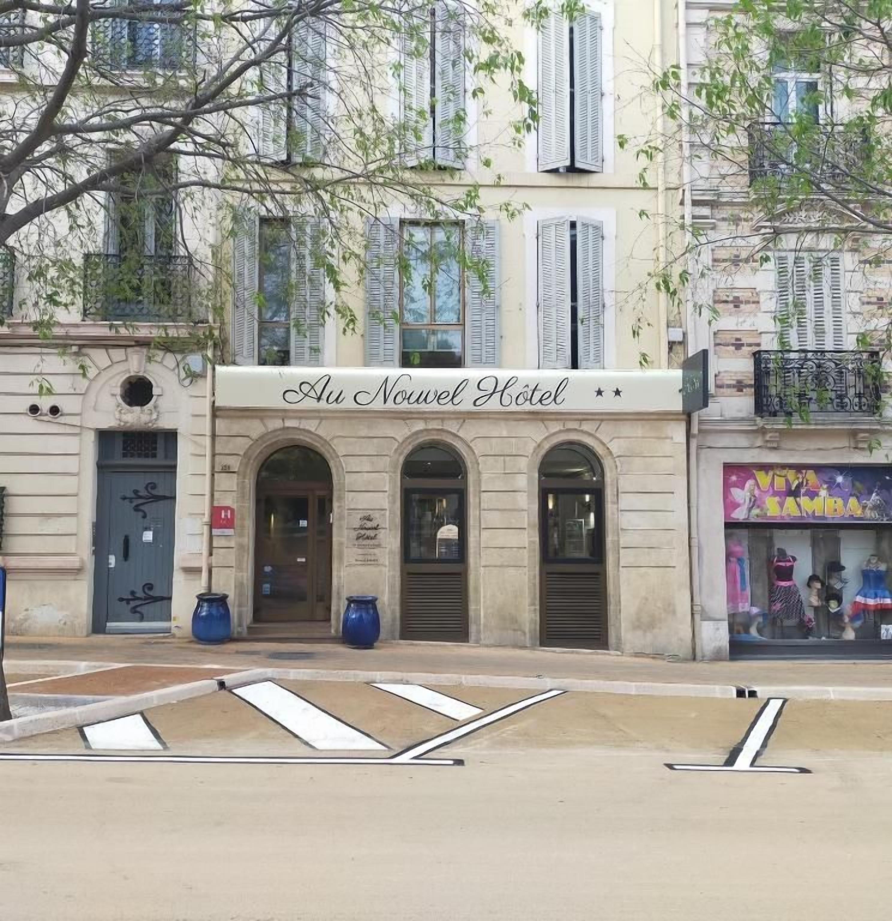 A hotel facade with a sign reading 'Au Nouveau Hotel' and a storefront with 'Viva Bambara' visible.