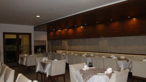 Una zona de dinar amb diverses taules preparades per al servei, cadires disposades al voltant de cada taula i un mur de panells de fusta al fons.