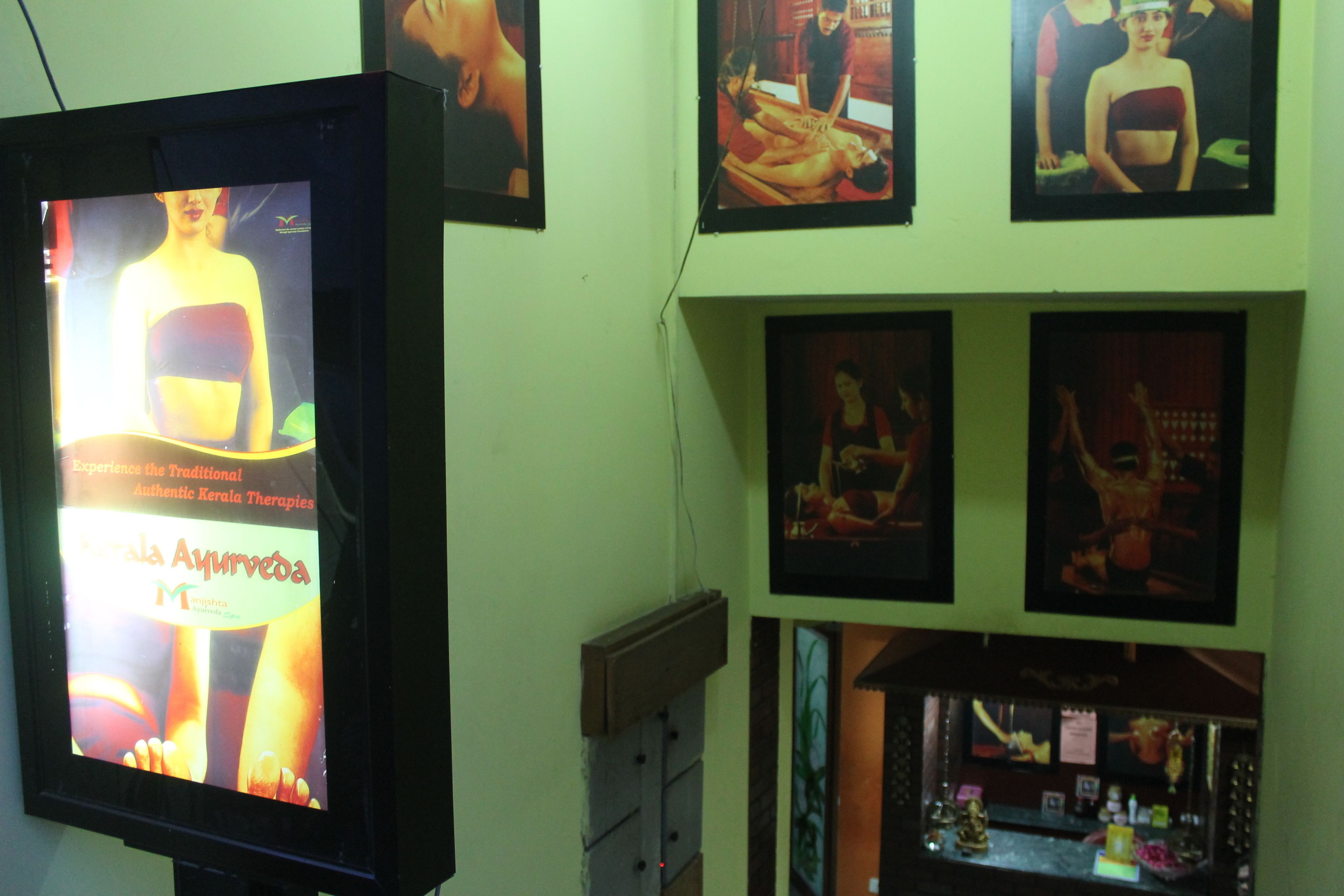 A wall with framed pictures and a television screen displaying a yoga advertisement.